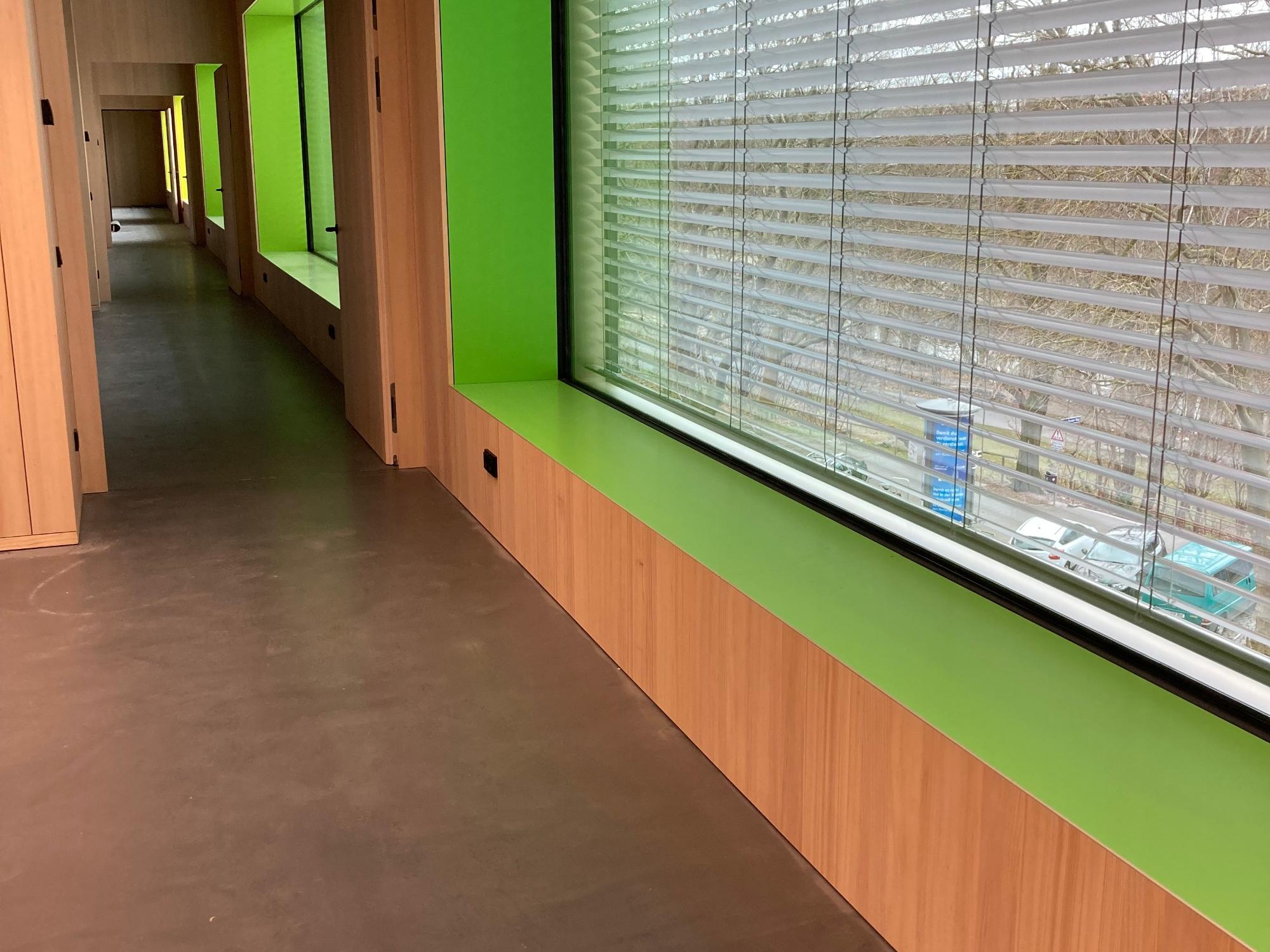 Blick auf ein Fenster innerhalb eines Klassenzimmers, umrahmt mit freundlichen Farben